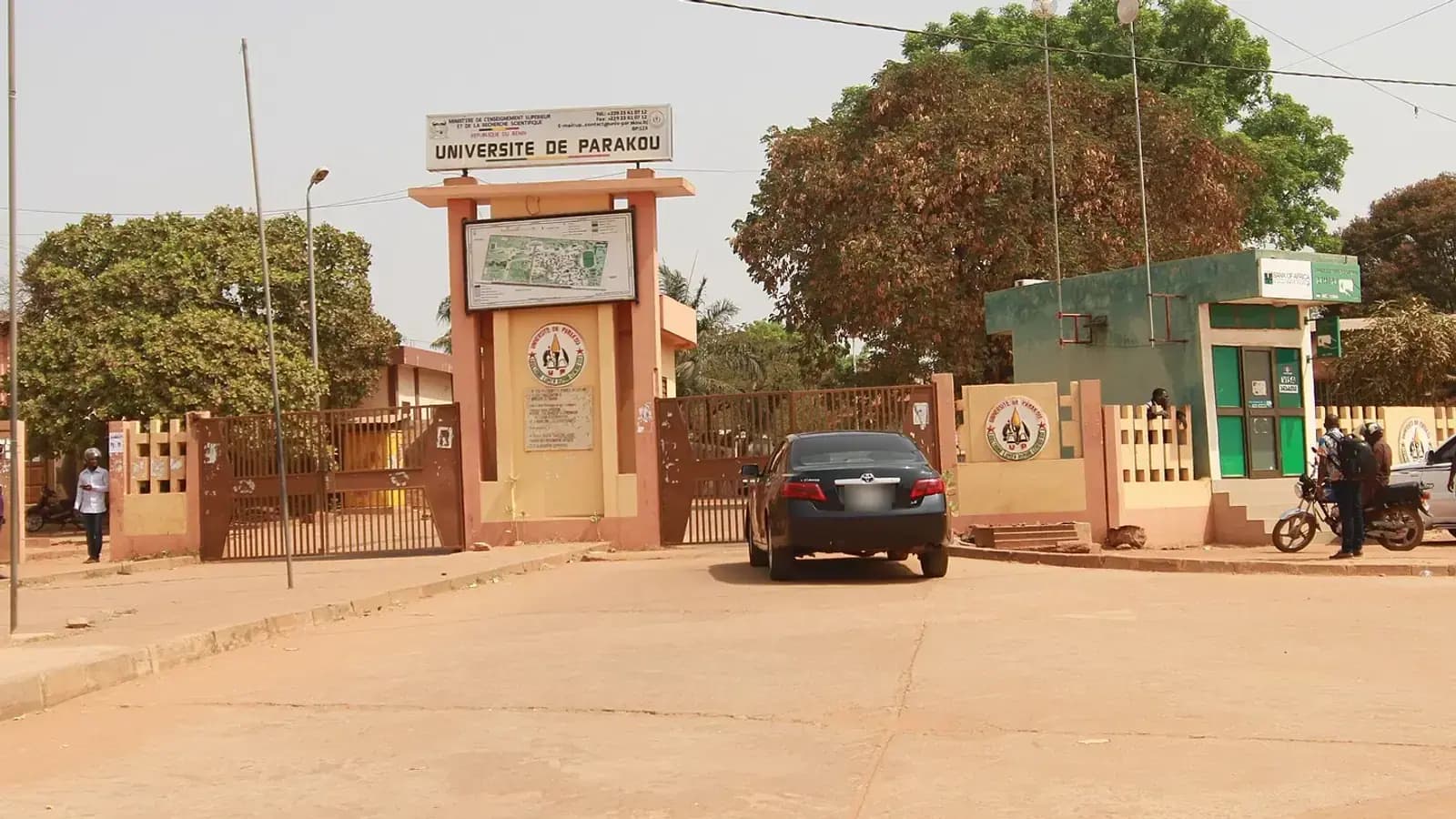 L'entrée de l'Université de Parakou : portail, panneau d'accueil et grands arbres